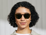 Model trägt Moscot Lemtosh Sun in Größe 52, Farbe Bamboo, Calibar Green Gläser
